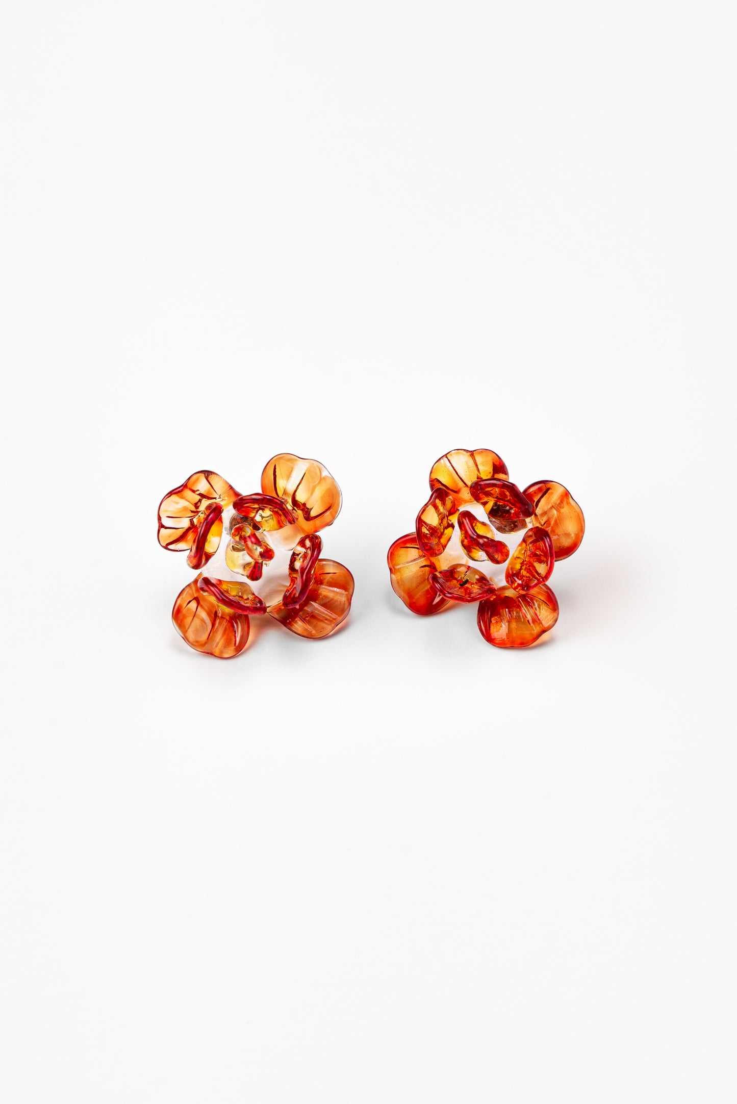 Pair of flower-shaped earrings made from translucent recycled glass in vibrant amber and red tones