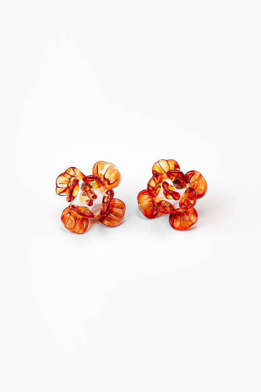 Pair of flower-shaped earrings made from translucent recycled glass in vibrant amber and red tones