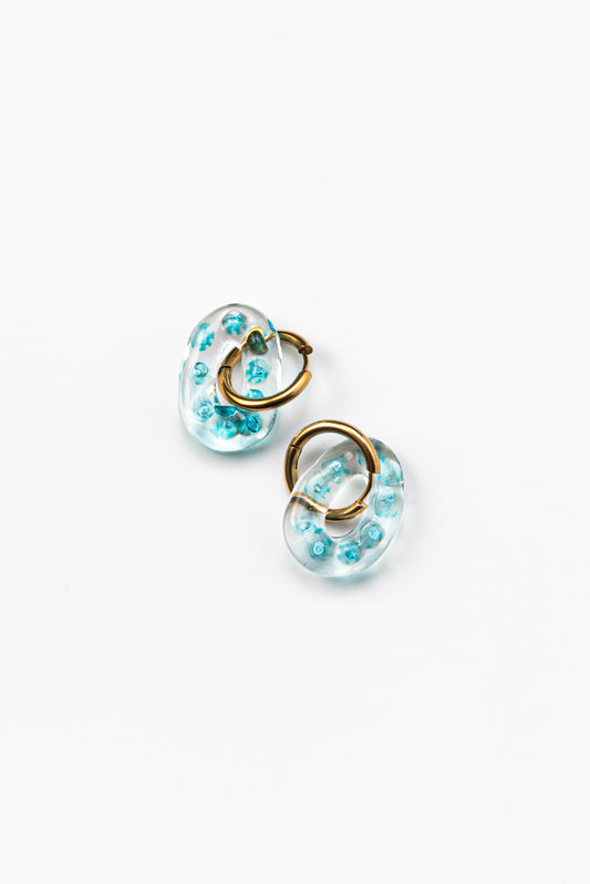 Clear oval earrings with little turquoise spheres inside, on a golden hoop, made from recycled glass