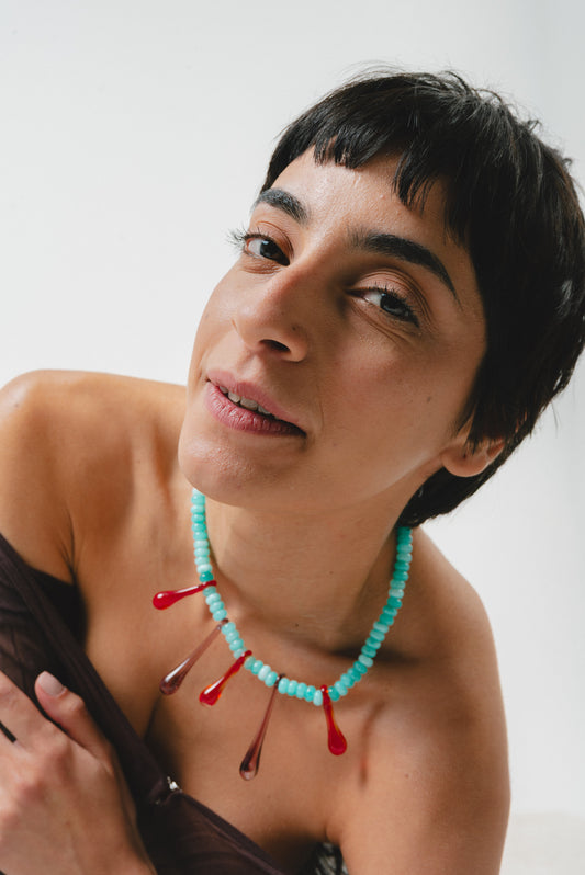 A statement necklace made of turquoise gemstone beads and red recycled glass drop pendants