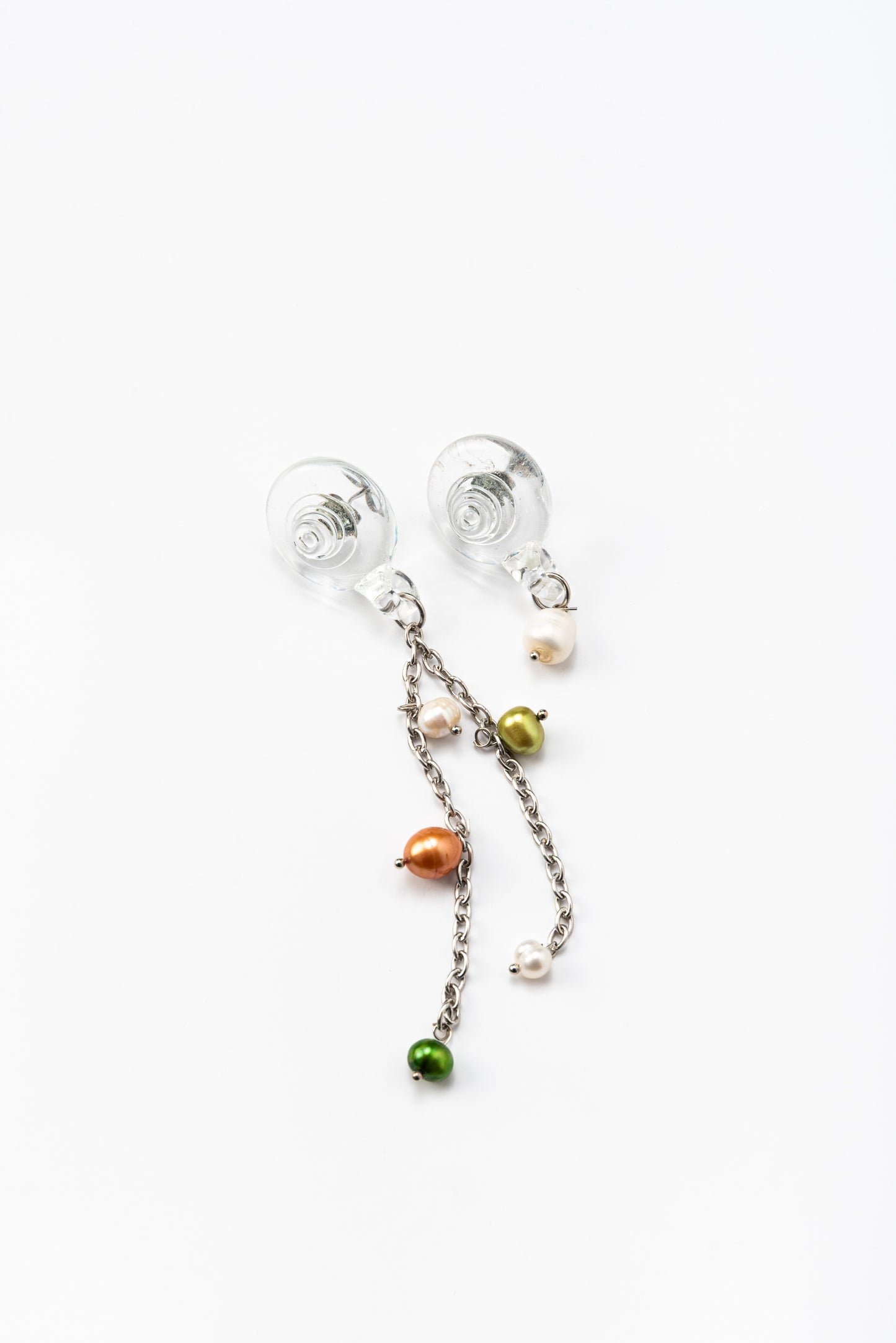Drop earrings with clear shell-shaped studs made of recycled glass. Each earring has a silver chain hanging down, with small round pearls in green, orange, and white attached at different points along the chain.