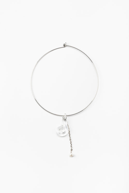 A silver necklace featuring a clear pendant in the shape of a shell, made from recycled glass, and a drop chain with a white pearl at the end