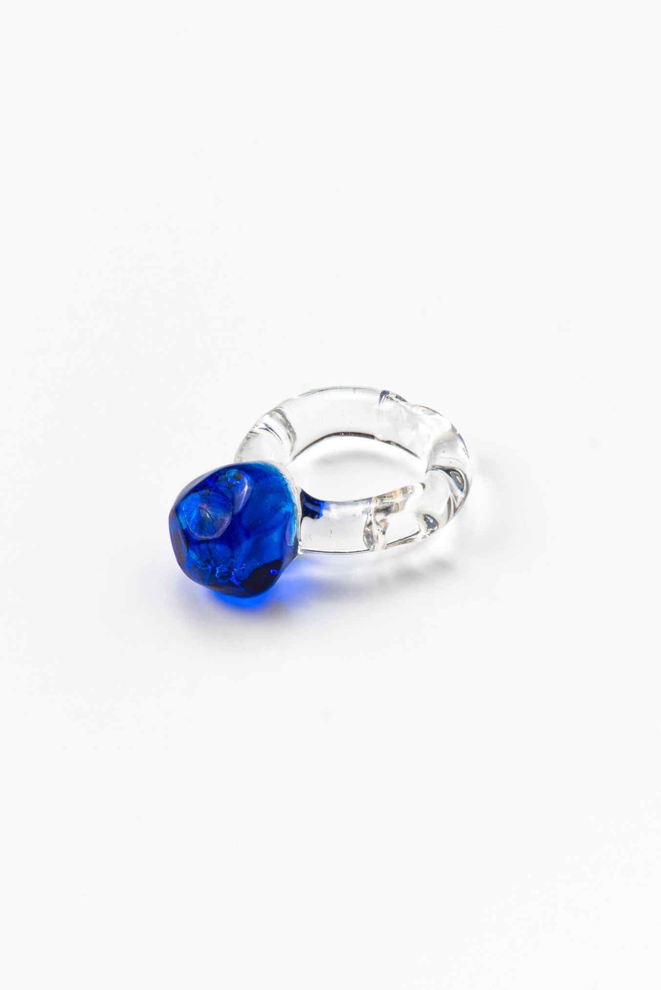 A clear Bolon ring with a dark blue-coloured sphere on top, made from recycled glass
