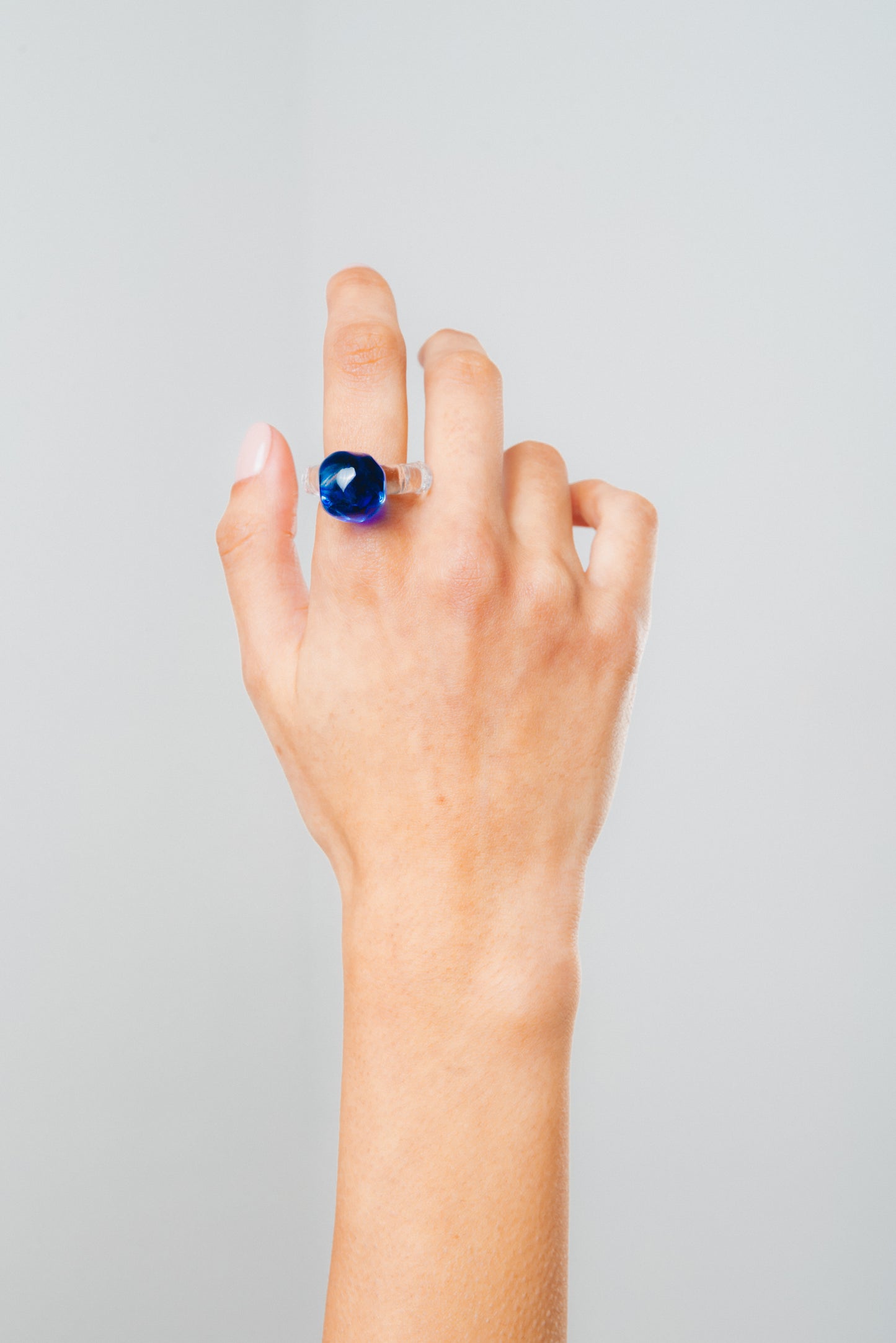 A clear Bolon ring with a dark blue-coloured sphere on top, made from recycled glass.