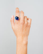 A clear Bolon ring with a dark blue-coloured sphere on top, made from recycled glass.