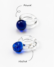 A clear Bolon ring with a dark blue-coloured sphere on top, made from recycled glass