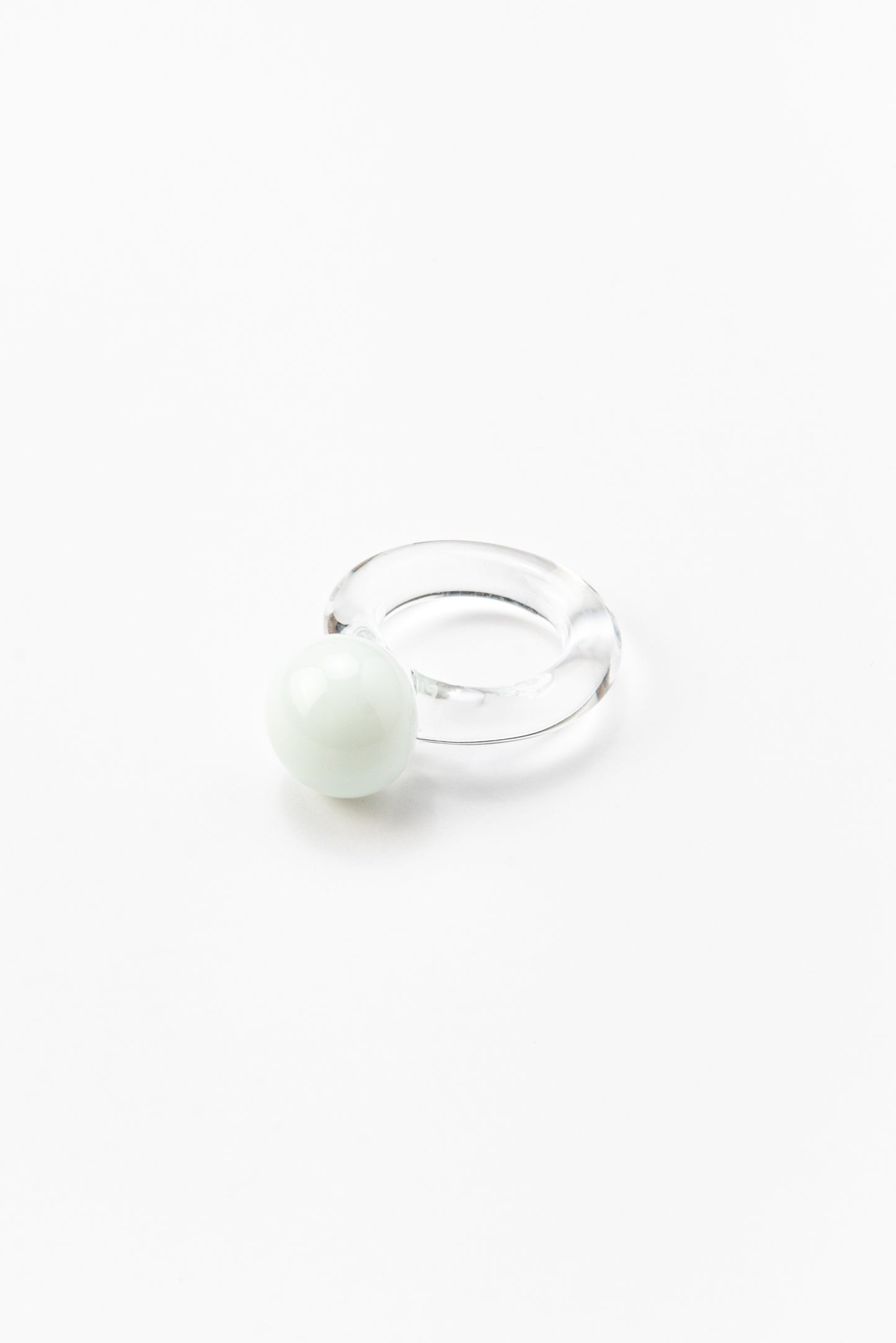 A clear Bolon ring with a white sphere on top, handcrafted from recycled glass