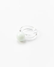 A clear Bolon ring with a white sphere on top, handcrafted from recycled glass