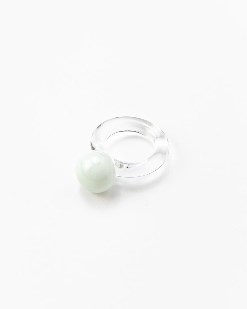 A clear Bolon ring with a white sphere on top, handcrafted from recycled glass