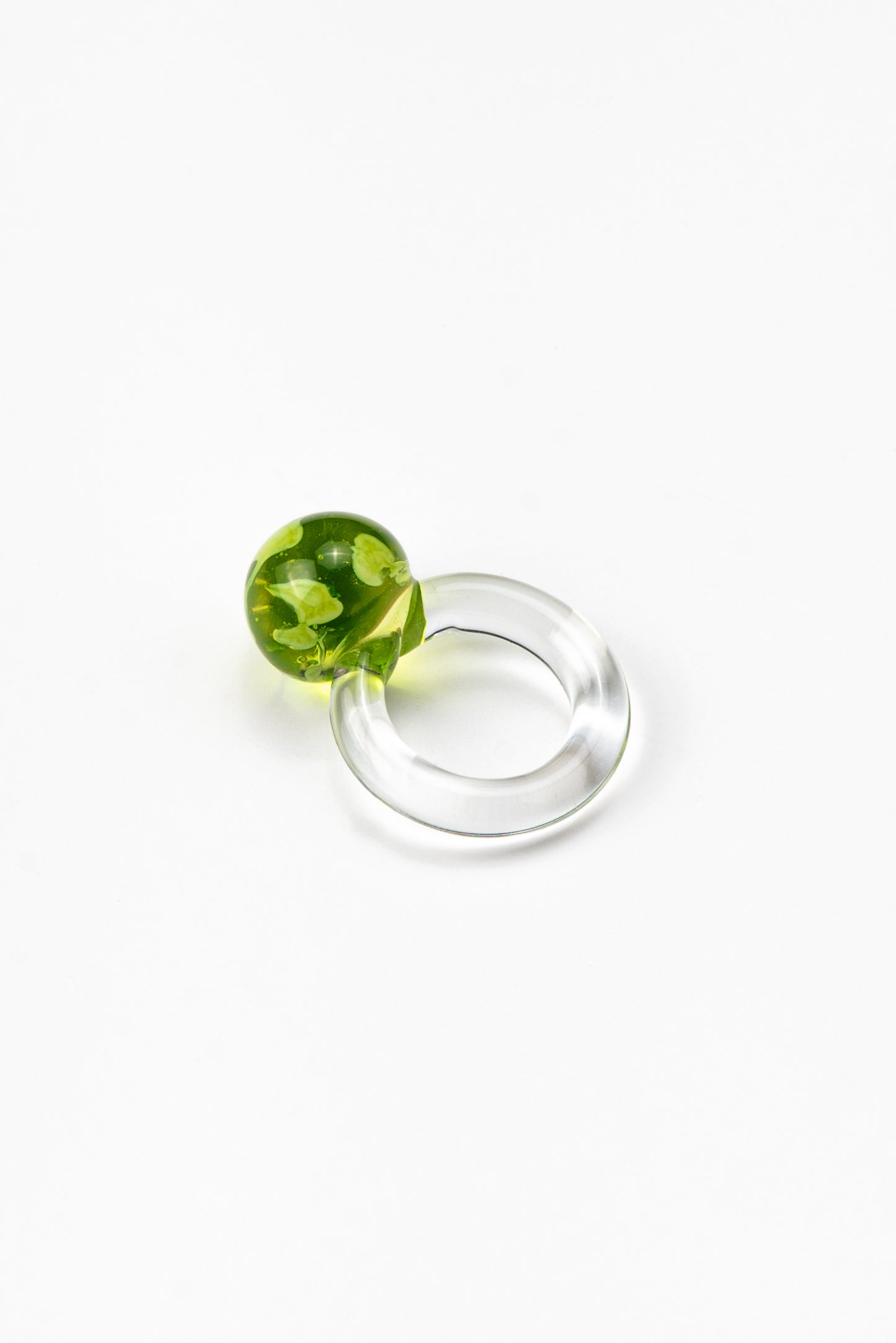 A clear Bolon ring with an apple green sphere on top, handcrafted from recycled glass