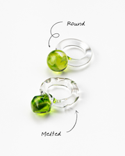 Two different styles of clear Bolon ring with an apple green sphere on top, handcrafted from recycled glass