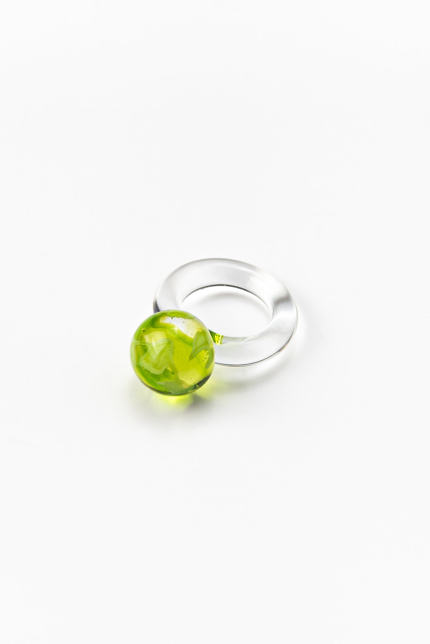 A clear Bolon ring with an apple green sphere on top, handcrafted from recycled glass