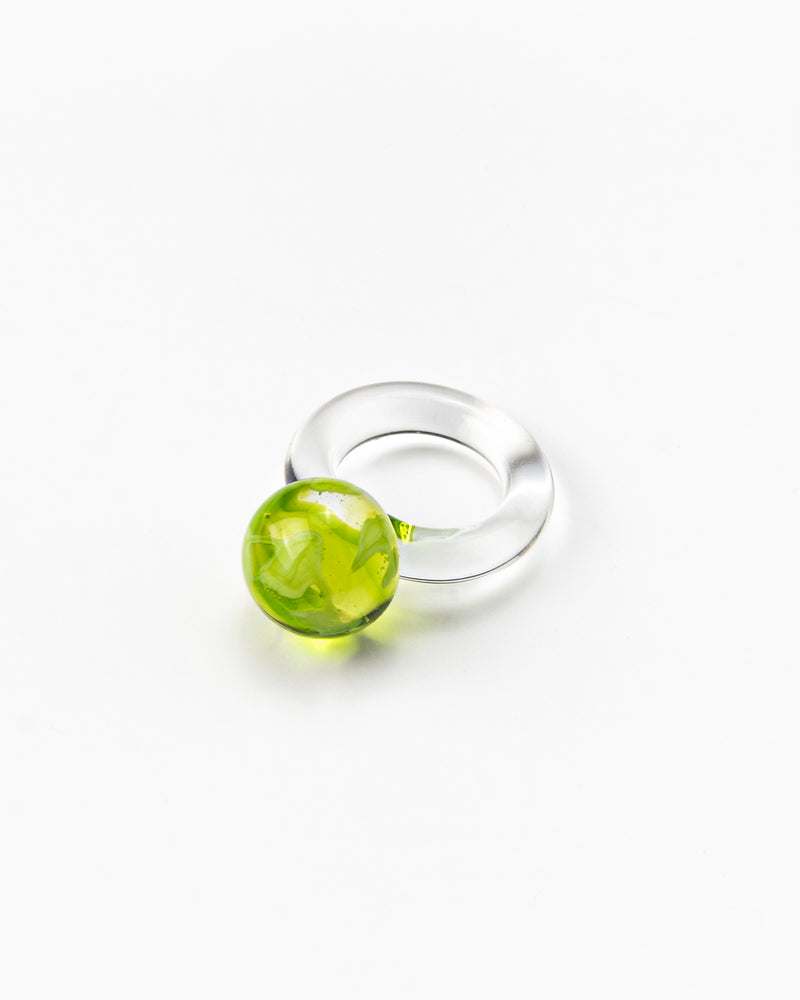 A clear Bolon ring with an apple green sphere on top, handcrafted from recycled glass