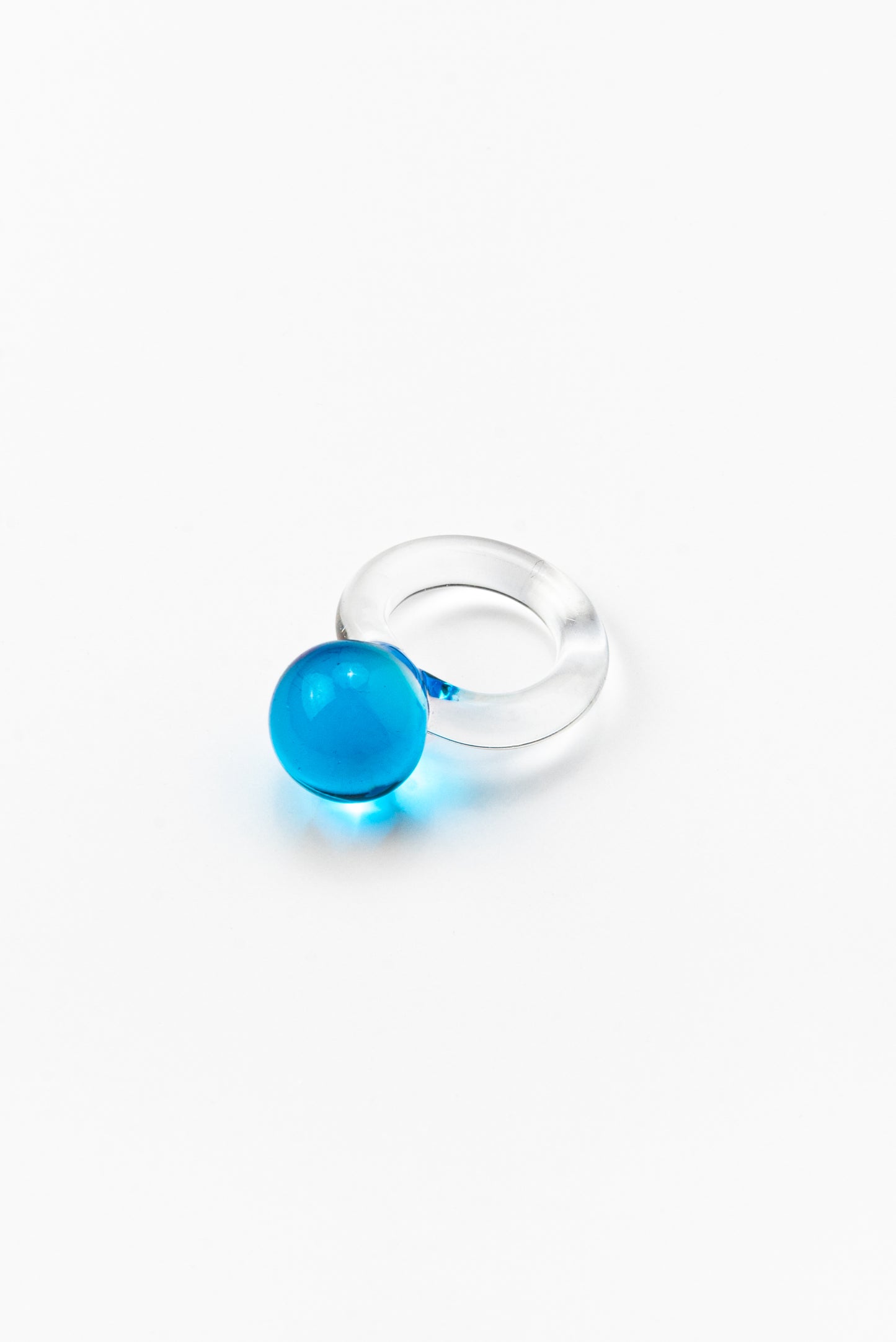 A clear Bolon ring with a sky blue-coloured sphere on top, handcrafted from recycled glass