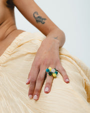 Clear ring with glass spheres, bubbles in green, yellow, and peach tones, made from recycled glass.