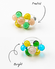 Two different variants of the same ring with glass spheres, bubbles in green, yellow, turquoise, and peach tones, made from recycled glass.