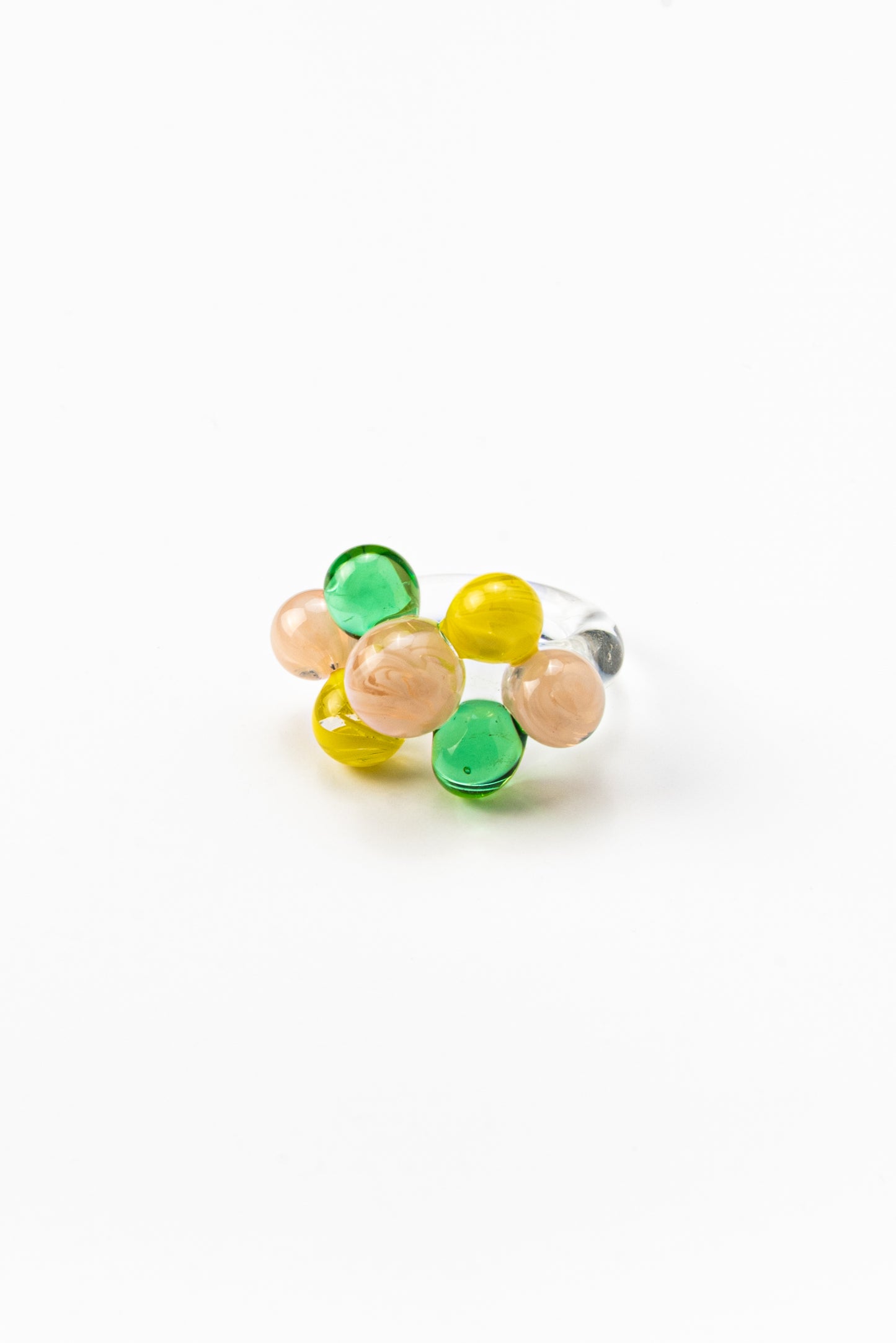 Clear ring with glass spheres, bubbles in green, yellow, and peach tones, made from recycled glass.