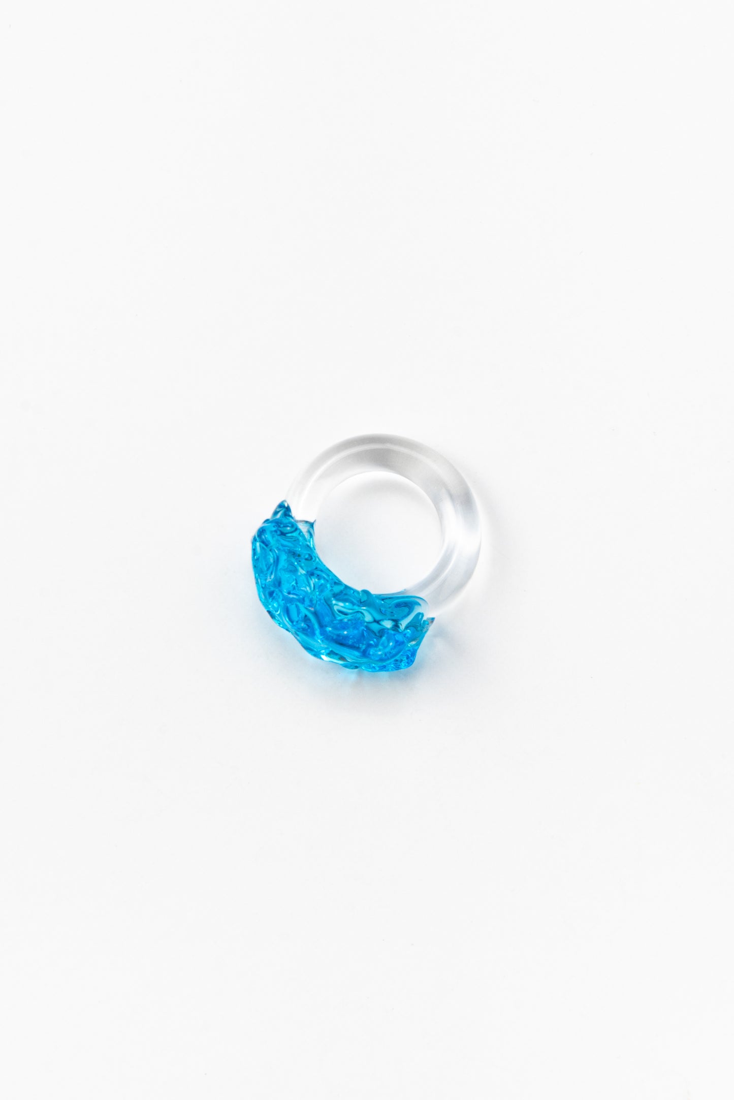 Clear ring with a bright turquoise textured glass detail on top, made from recycled glass.